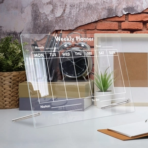 Detailed view of clear acrylic weekly planner board on desktop with metal stands