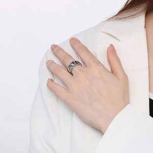 Close-up of heart-shaped silver ring on finger with white suit background