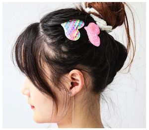 Détail des barrettes à cheveux en forme de cœur avec paillettes colorées et roses