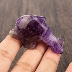 Handheld purple crystal dolphin carving showing natural texture and translucent finish