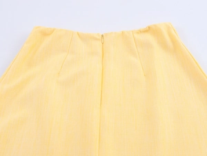 Detail of the yellow skirt's waist featuring a neat invisible zipper and linen texture