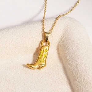 Gros plan d'un collier doré avec pendentif de botte de cowboy sur fond en peluche beige