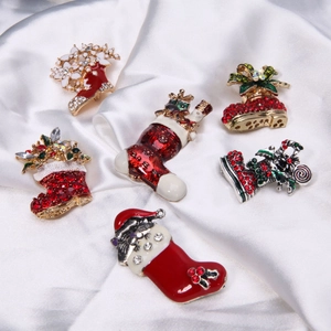 Detail of six Christmas brooches with colorful enamel and rhinestones on white silk fabric