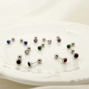 Macro shot of colorful zircon dumbbell earrings on a decorative white ceramic plate