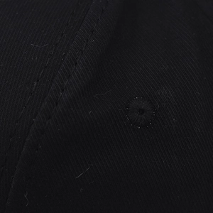 Close-up of black washed cotton baseball cap fabric showing twill texture and eyelet detail