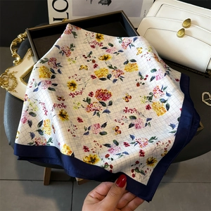 Detailed macro view of silk scarf texture with floral and butterfly print in navy border