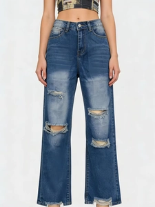 Detailed view of ripped denim jeans featuring washed blue texture and fringe distressed holes