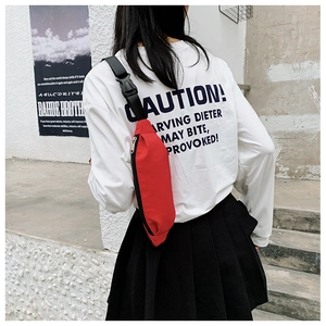 Rear view of a red canvas fanny pack with black nylon strap worn as a cross-body bag