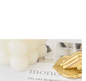 Detail einer goldenen Süßwasserperlenkette mit Kerze und modernem Magazin im Hintergrund