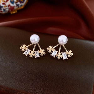 Dettaglio macro di orecchini di perle placcati in oro 14k con design a croce e fiori