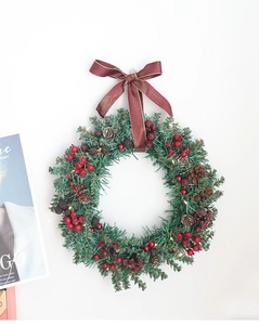 Detail of Christmas wreath with red berries, pine cones, velvet bow and LED fairy lights