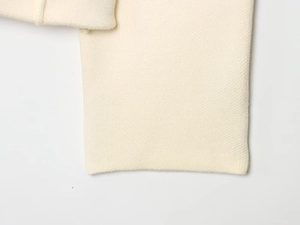 Detailed macro view of the cream-colored knit fabric texture and premium stitching