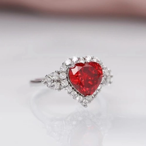 Detailed view of silver ring with large heart-shaped red zircon and pavé crystal accents