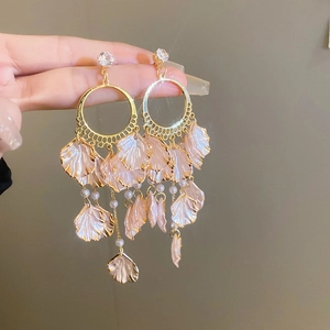 Detail of elegant gold earrings with pink shell petals, pearls, and tassel drop design
