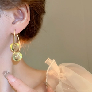 Detail of elegant yellow-green translucent bead earrings with gold metal hooks on person