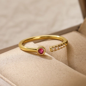 Macro detail of gold-plated open ring with red ruby zircon and micro-pave white stones