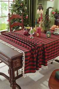 Macro detail of red and green plaid tablecloth with white tassels for festive Christmas decor