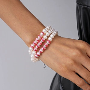 Vue détaillée du bracelet à trois rangées de perles de verre avec texture rose sur poignet
