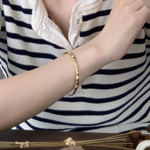 Detail of minimalist gold textured bangle featuring organic branch-like patterns on wrist