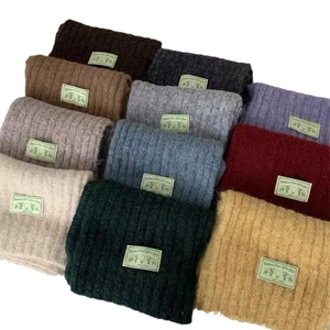 Multiple colors of warm knitted wool blend scarves folded neatly on a white background
