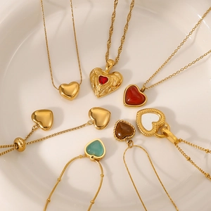 Various heart pendant necklaces in gold and assorted colors on a white ceramic plate