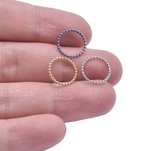 Three beaded stainless steel rings in rainbow gold and silver on a finger