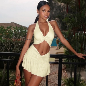 Detail of light yellow ruched halter top and mini skirt set on tropical resort background