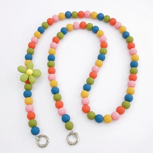 Macro detail of colorful matte beads with green flower charm and silver ring clasps