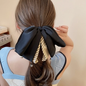 Détail d'une grande pince à cheveux à nœud en soie noire et tissu rayé avec perles