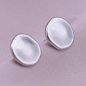 Macro shot of silver bow knot earrings with organic texture and mirror finish