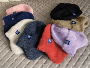Vista piatta di berretti in maglia in otto colori con etichette blu a fiocco di neve