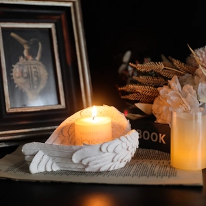 White resin angel wing candle holder sculpture with detailed feather texture and candle