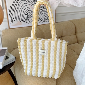 Detail of yellow and white striped bubble texture fabric tote bag on a cozy sofa