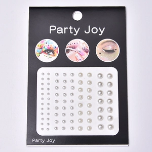 Close-up of white multi-size pearl face stickers on black card for party makeup