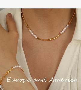 Close-up of gold metal chain necklace and bracelet set featuring white freshwater pearls