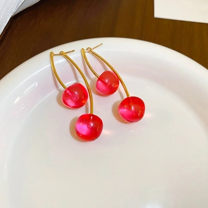 Close-up of elegant cherry drop earrings with transparent red beads and golden hooks