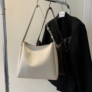 Detail view of large minimalist leather tote bags in cream and dark brown colors