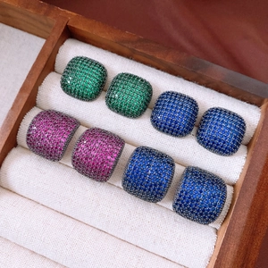 Macro detail of vintage square earrings with inlaid zircon in emerald and royal blue