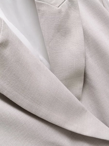 Close-up of premium textured light gray blazer lapel with high-density fabric stitching