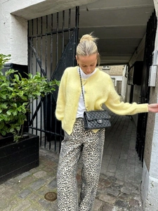 Chic pale yellow knit cardigan paired with leopard print trousers on a sunny street
