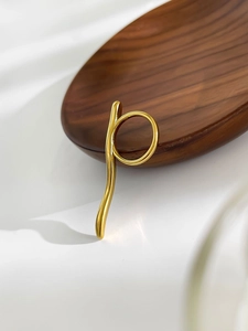 Détail d'une bague ondulée minimaliste plaquée or 18 carats sur soie et bois sombre