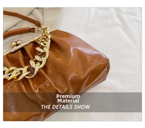 Detail of vintage brown oil leather bag featuring a chunky gold chain and sphere clasp