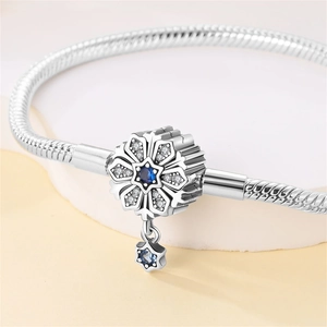 Macro shot of silver snake chain with snowflake charm featuring a blue gemstone and S925 mark