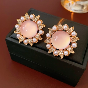 Détail de boucles d'oreilles tournesol vintage avec perles sur un coffret en cuir noir