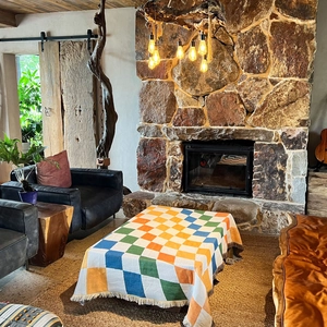 Colorful checkered knit picnic blanket with tassels on a vintage leather sofa
