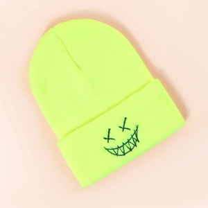 Detailed view of neon yellow knit beanie featuring a black embroidered funny face patch