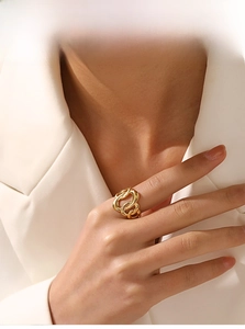 Detail of interlocking gold weave ring worn by model in professional white suit