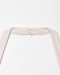 Detailed view of halter neck closure with two white buttons on textured cream woven fabric