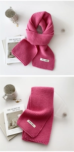Detail of pink knitted winter scarf showing soft texture and brand label on white table