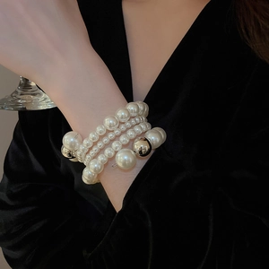 Detail of multilayer pearl bracelet featuring varied bead sizes and silver sphere accents